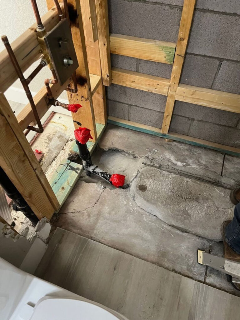 Copper water lines and capped drainage pipes installed within wood framing during a bathroom renovation.