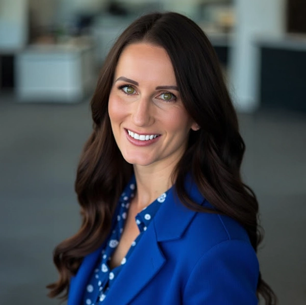 Professional woman with dark hair and blue blazer smiling in an office for Smart Choice Remodeling.