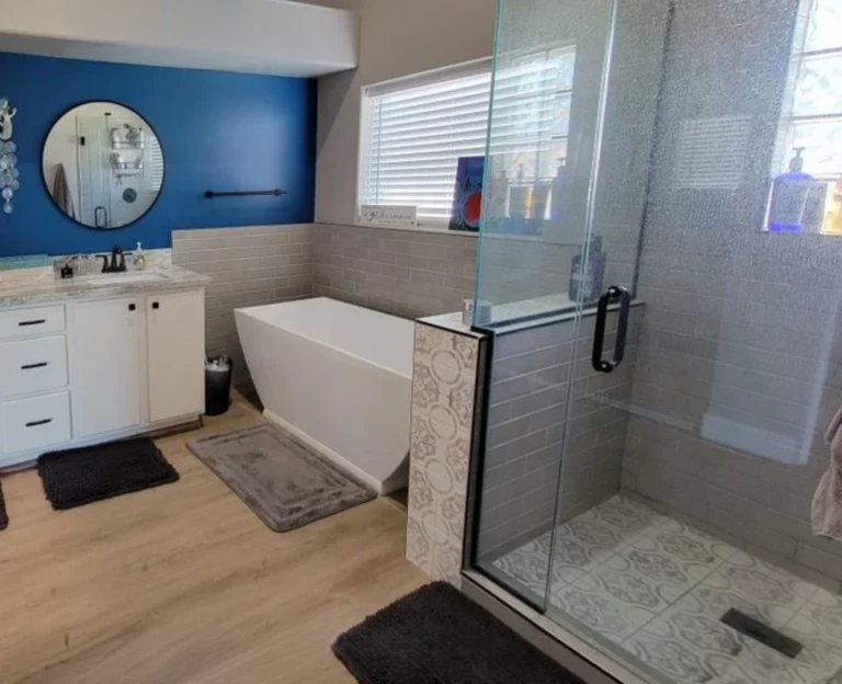 Modern master bathroom featuring a white freestanding soaking tub, walk-in glass shower, and blue accent wall.