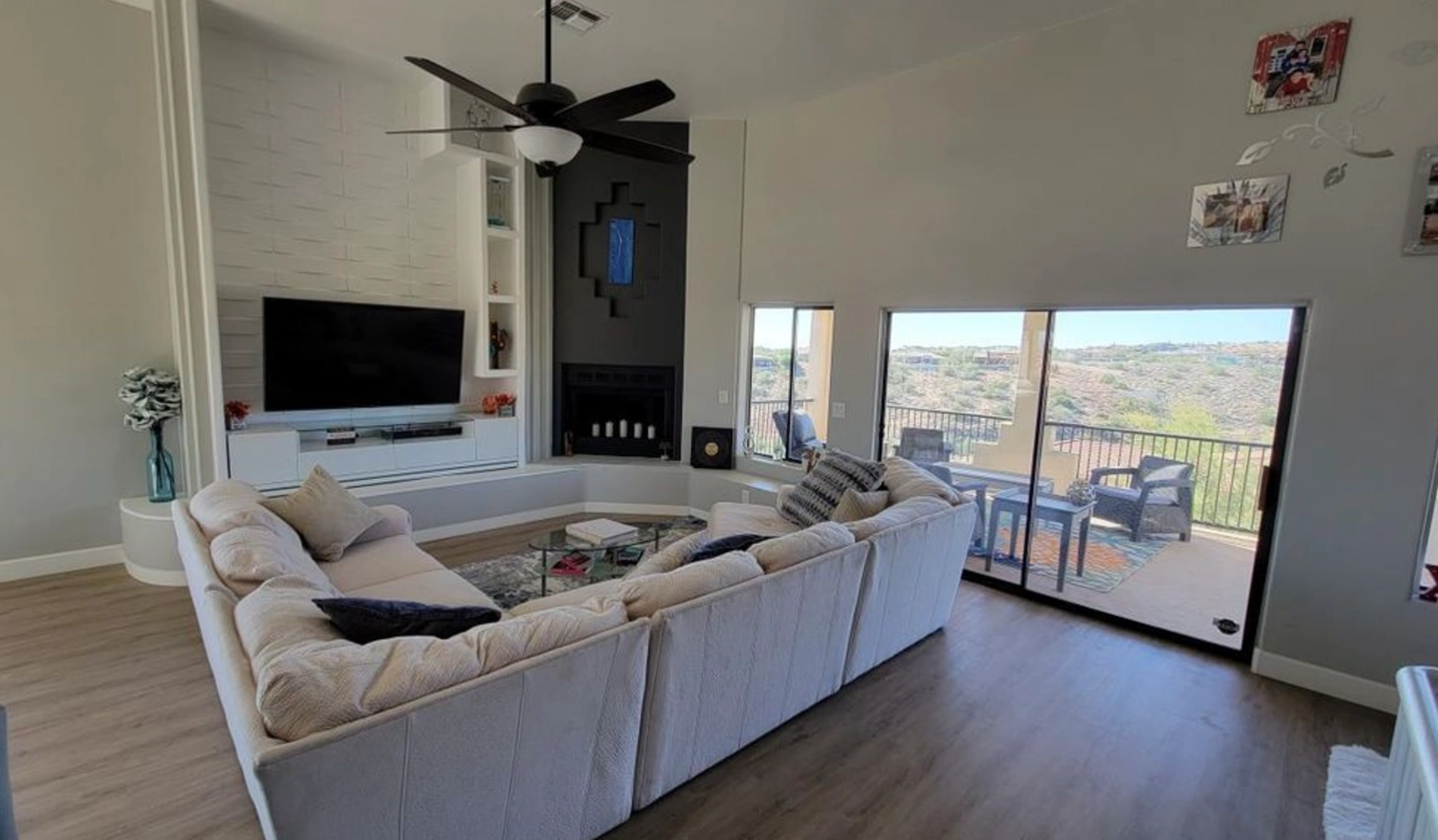 Large white sectional sofa in a modern living room with a black corner fireplace and sliding glass balcony doors.