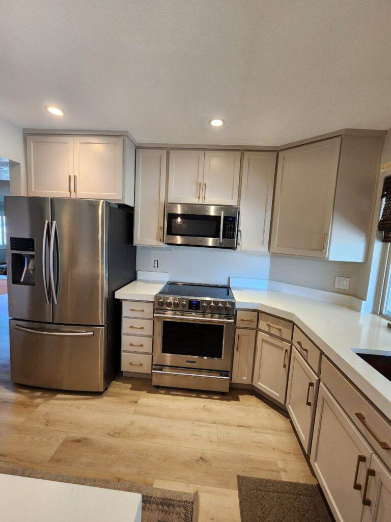 Modern kitchen featuring light grey shaker cabinets, white countertops, and stainless steel appliances.