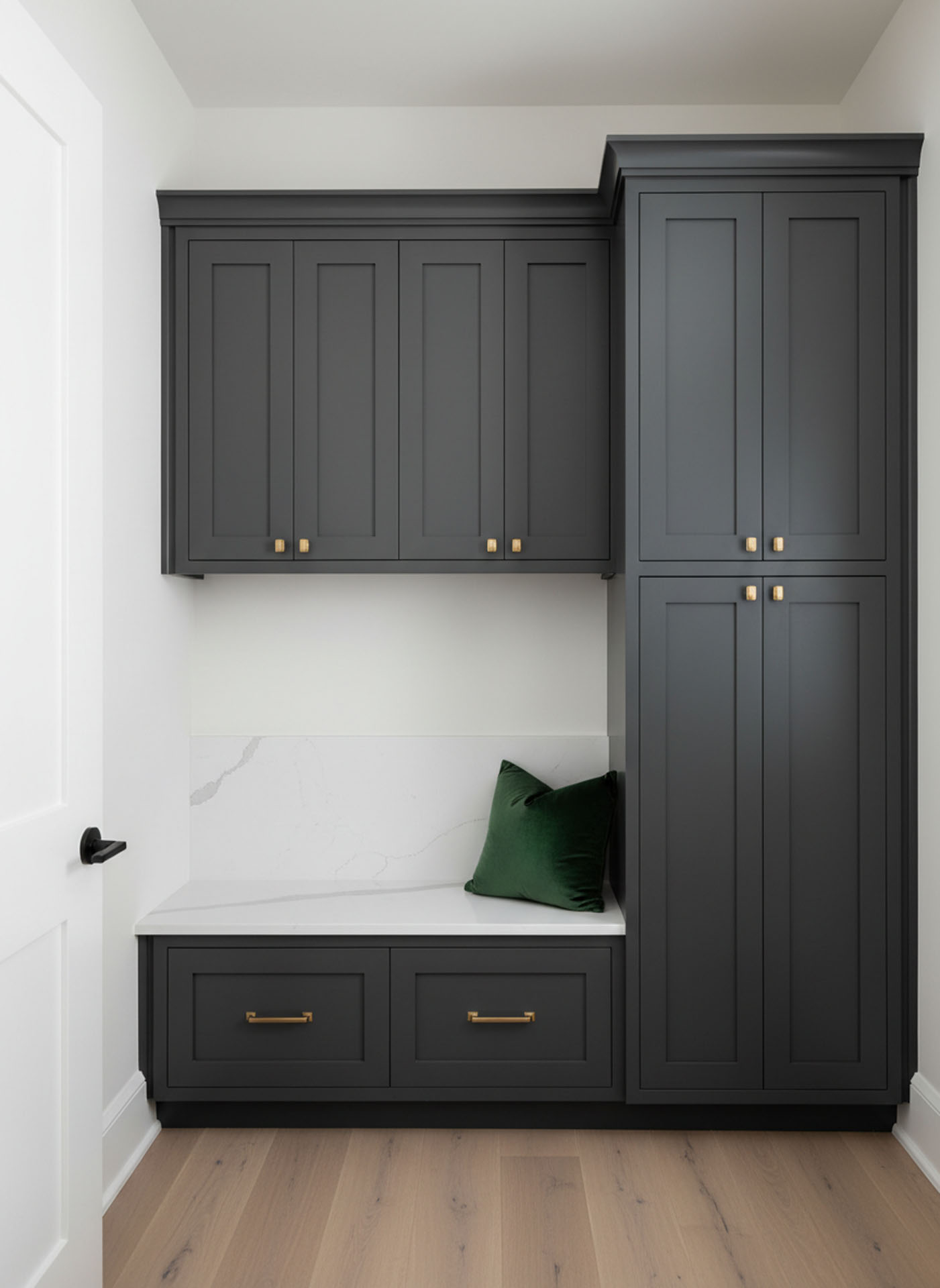 Elegant charcoal shaker-style cabinets with gold hardware and a white marble built-in bench in a mudroom.