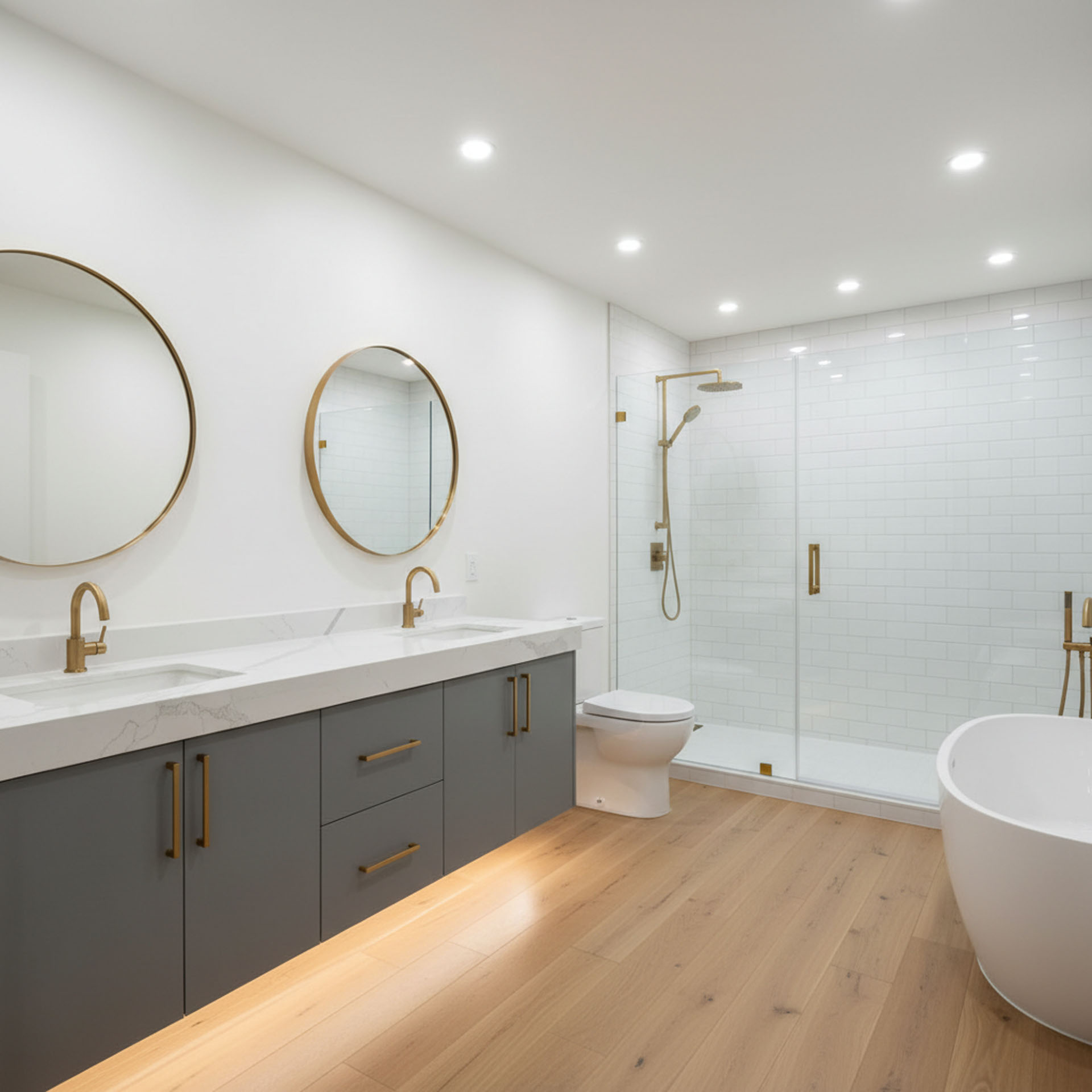 Contemporary bathroom with grey double vanity, gold faucets, round mirrors, and glass walk-in shower.