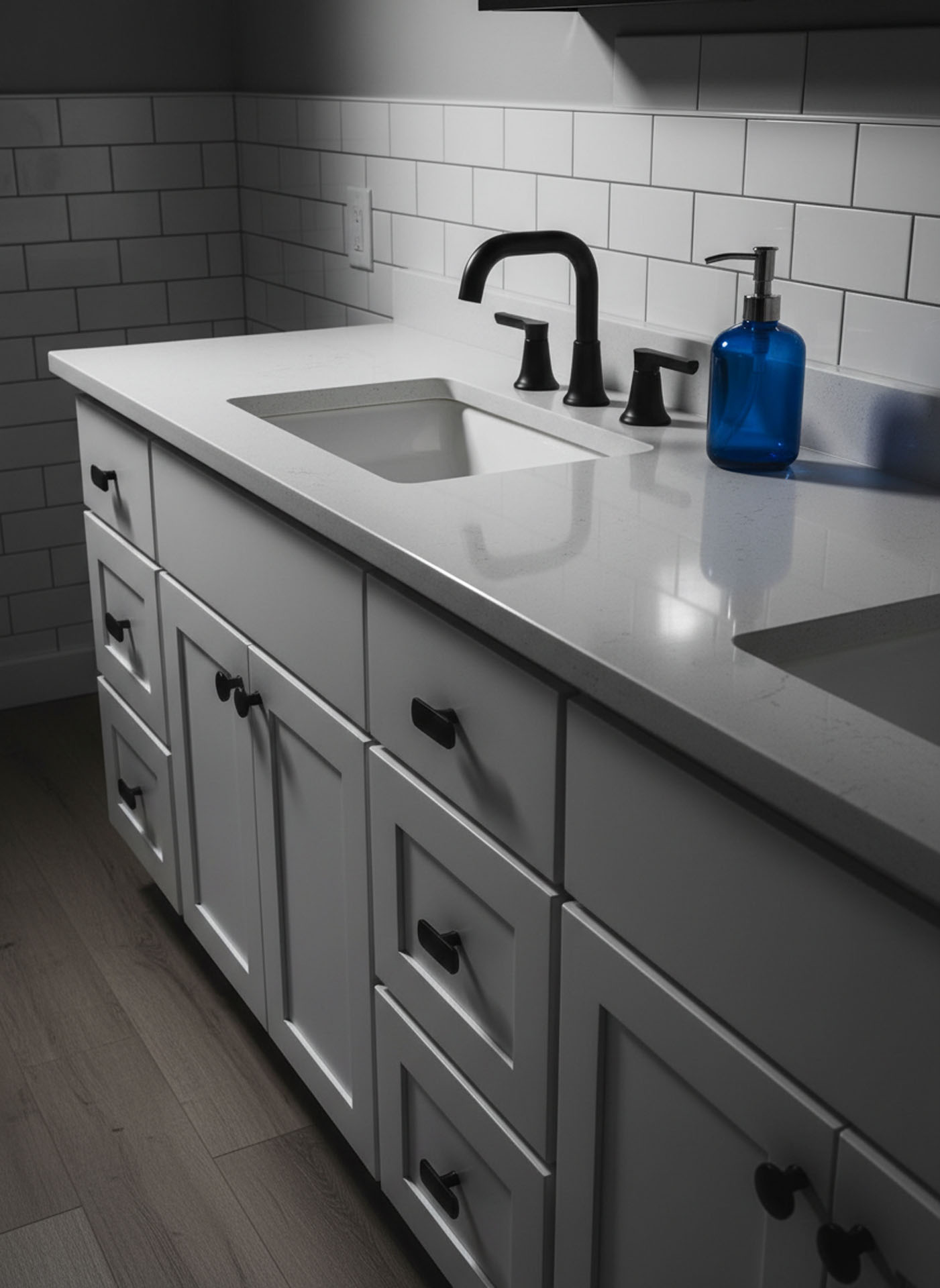 White shaker bathroom vanity featuring a quartz countertop, matte black faucet, and white subway tile backsplash.