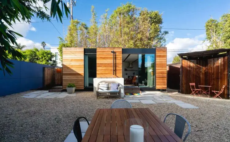 Modern wood-paneled backyard ADU with gravel courtyard, outdoor seating area, and lush bamboo landscaping.