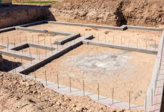 Freshly poured concrete footings and foundation with rebar in a construction trench for a new building.