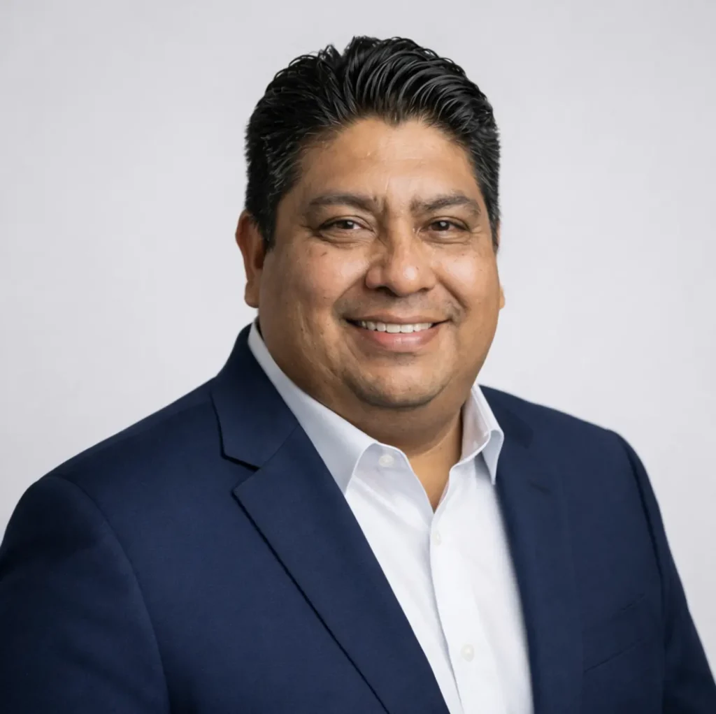 Professional man in a navy blazer and white shirt smiling for a business headshot.